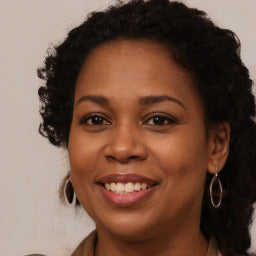 Woman with a warm smile, wearing earrings and a necklace.