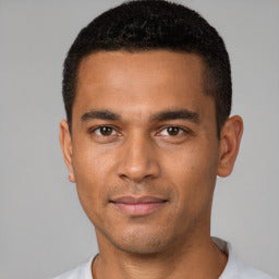 Man with short black hair wearing a light gray shirt against a neutral background